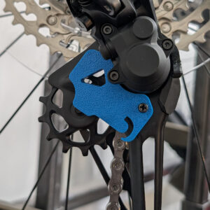 Blue 3D-printed Derailleur J Lock Tool attached to rear derailleur cage on a mountain bike
